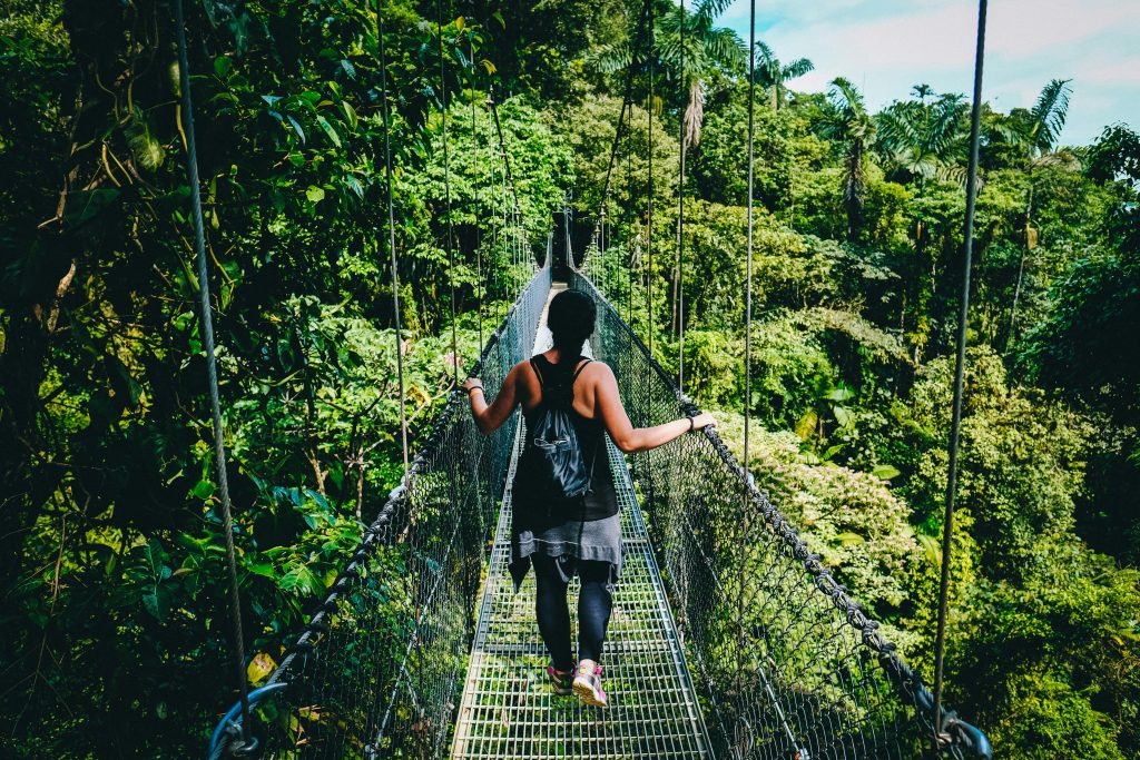 woman in black shirt and black pants standing on hanging bridge