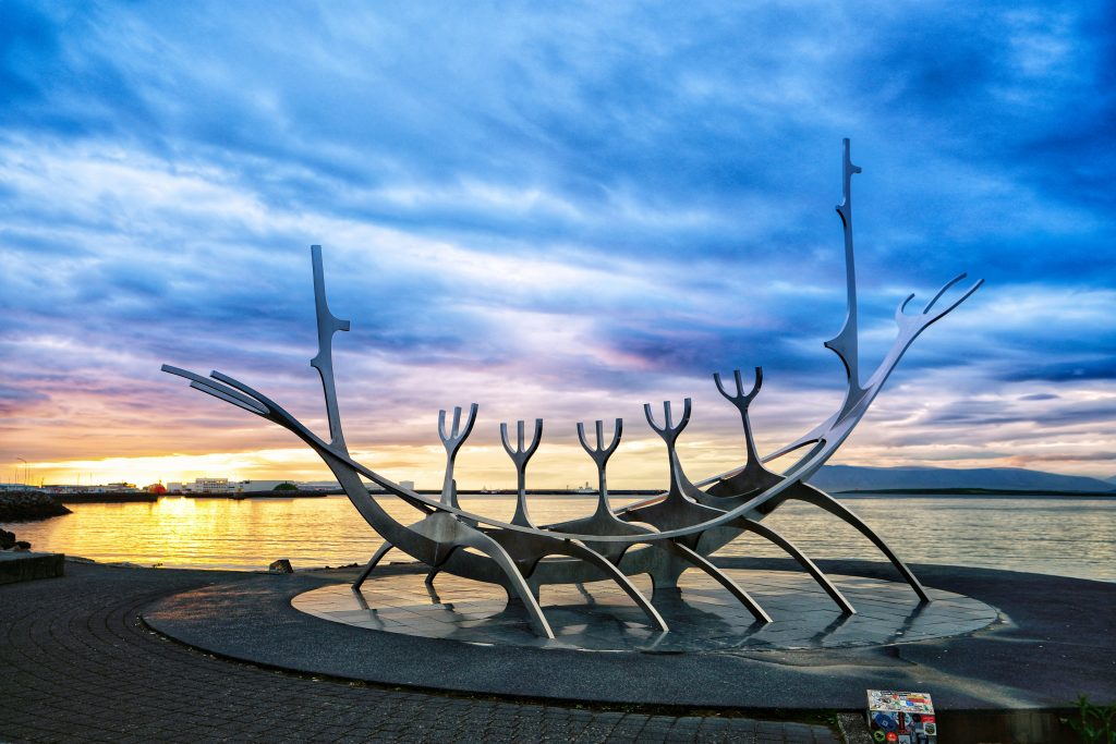 A large metal sculpture sitting next to a body of water