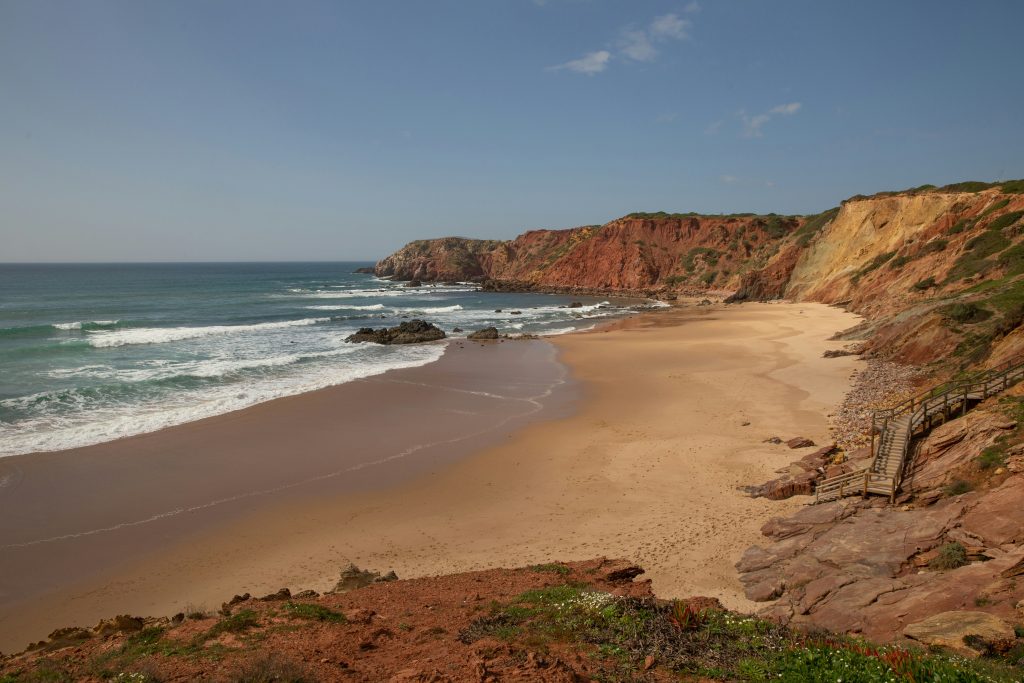 A sandy beach next to the ocean under a blue sky