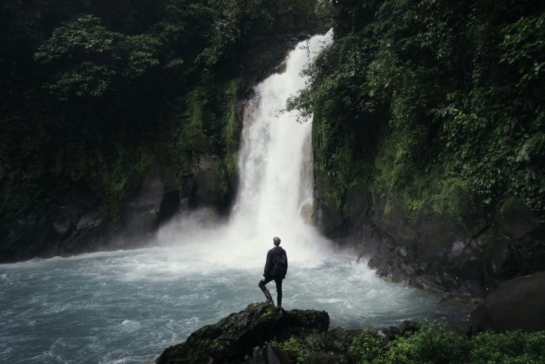 man-standing-on-cliff-near-falls man standing on cliff near falls
