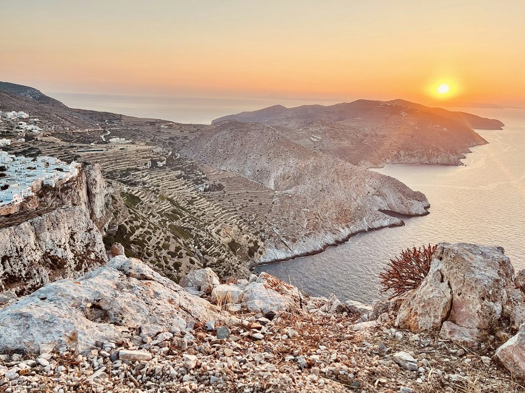 the sun is setting over the mountains and water