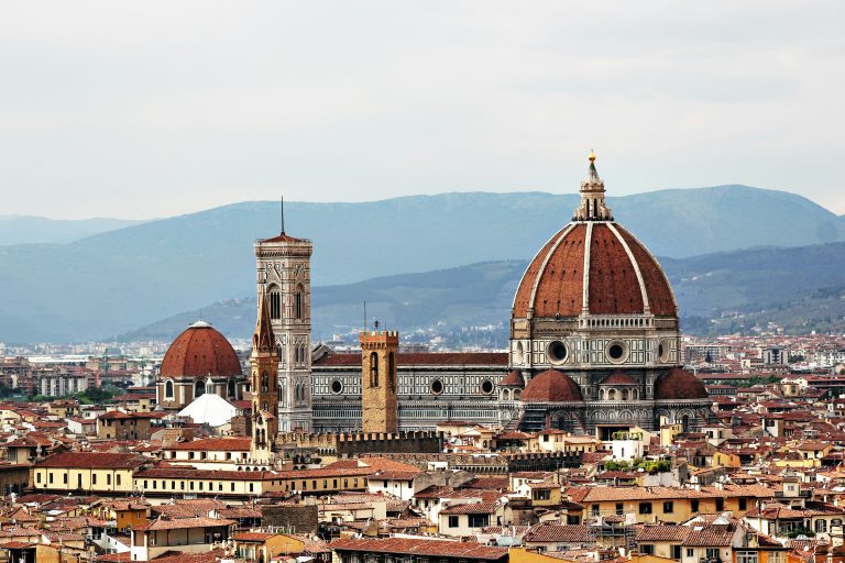 Florence's Duomo and bell tower rising above terracotta rooftops and distant hills
