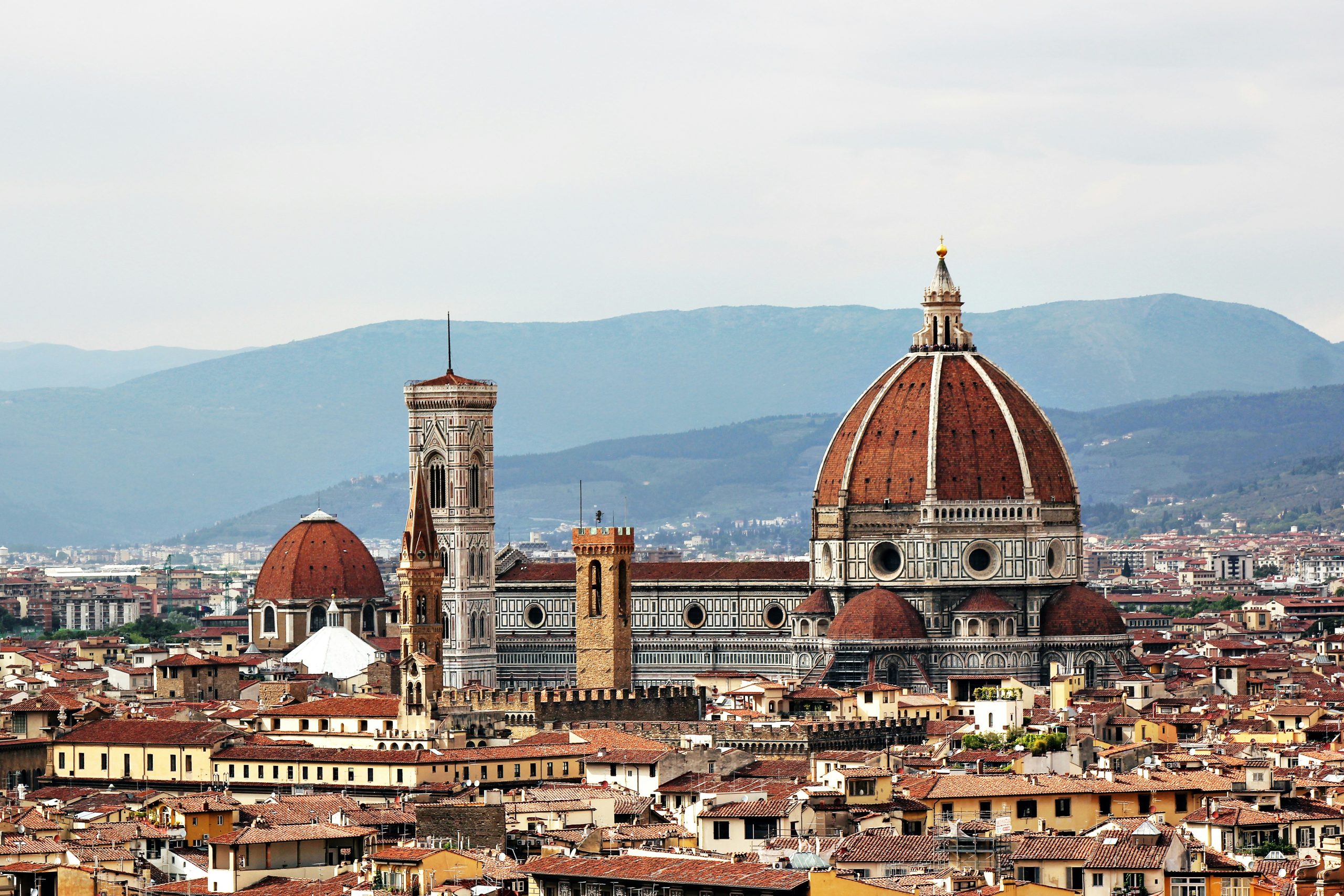 Florence's Duomo and bell tower rising above terracotta rooftops and distant hills