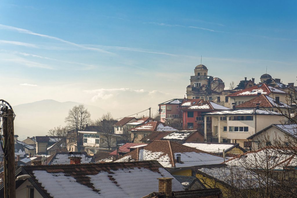 Snow-covered rooftops of a european town with mountains.