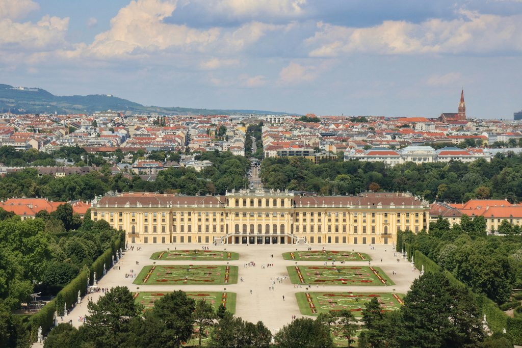 a large building with a courtyard and trees in front of it with Schönbrunn Palace in the background
