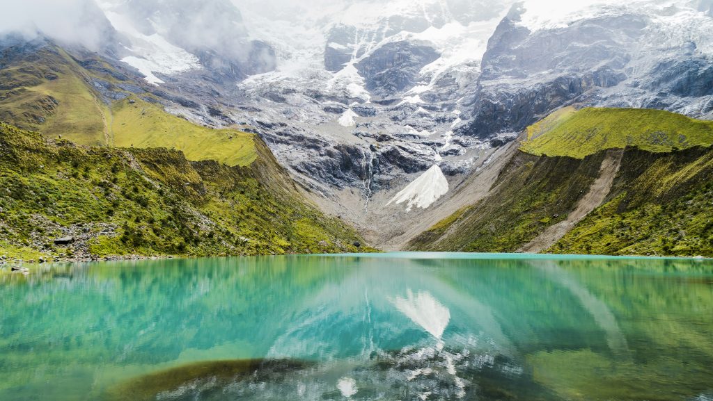 body of water with green mountains during daytime
