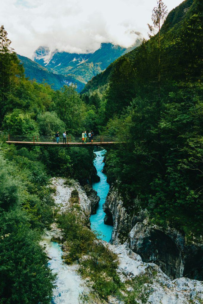 person in green jacket and black pants standing on bridge over river during daytime